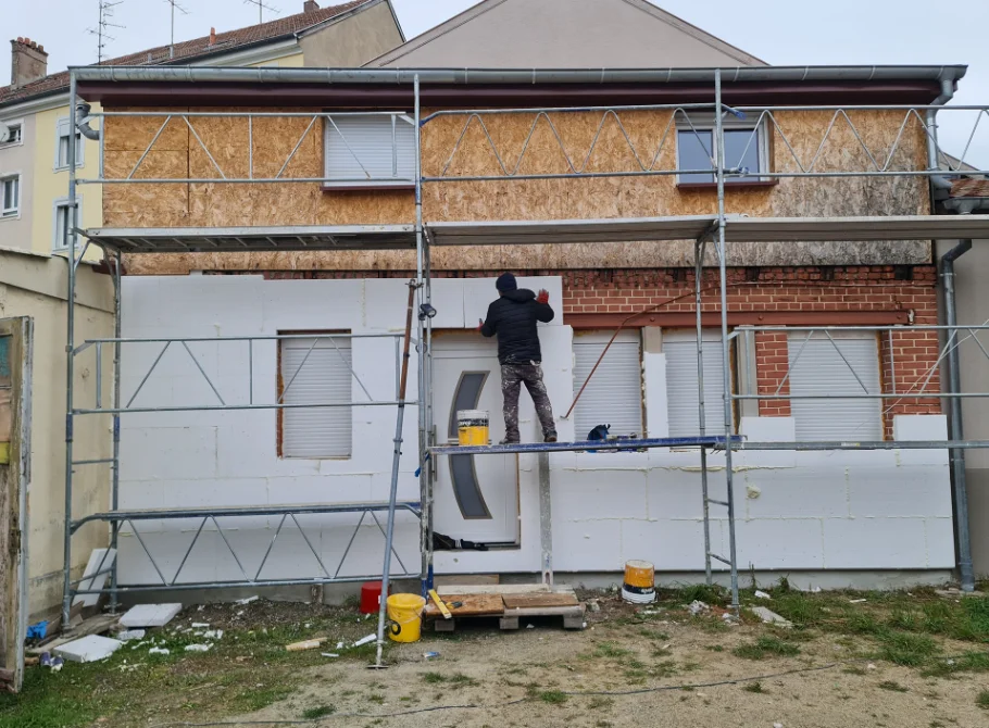 Ouvrier posant des panneaux d'isolation extérieure sur une façade – chantier Güven Rénovation à Mulhouse